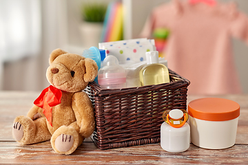 Image showing baby things in basket and teddy bear toy on table