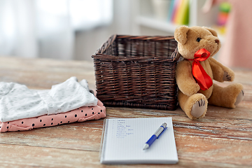 Image showing baby clothes, teddy bear, toy blocks and notebook