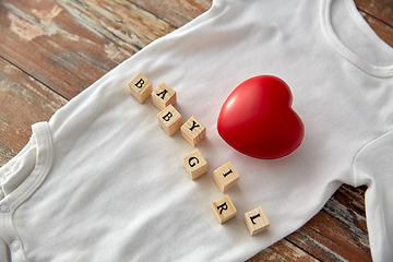 Image showing baby bodysuit with red heart on wooden table