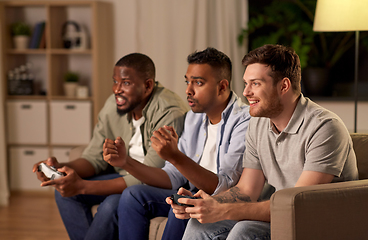 Image showing happy friends playing video games at home at night