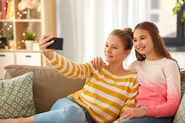 Image showing happy girls taking selfie with smartphone at home