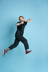 Image showing Portrait of young caucasian man looks happy, jumping on blue background