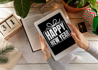 Image showing Female hands holding tablet with wishes of happy New Year and Merry Christmas