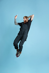 Image showing Portrait of young caucasian man looks happy, jumping on blue background