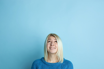 Image showing Portrait of young caucasian woman looks happy, dreamful on blue background