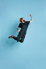 Image showing Portrait of young caucasian man looks happy, jumping on blue background