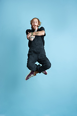 Image showing Portrait of young caucasian man looks happy, jumping on blue background