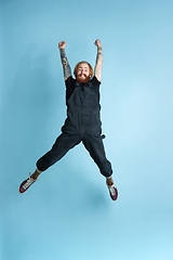 Image showing Portrait of young caucasian man looks happy, jumping on blue background