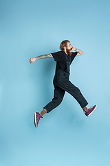 Image showing Portrait of young caucasian man looks happy, jumping on blue background