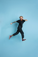 Image showing Portrait of young caucasian man looks happy, jumping on blue background