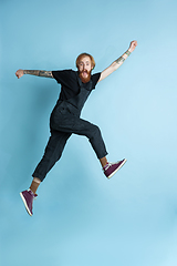 Image showing Portrait of young caucasian man looks happy, jumping on blue background