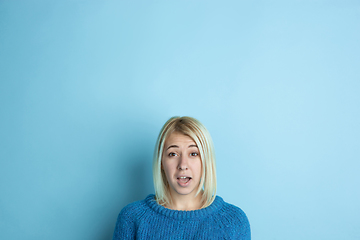 Image showing Portrait of young caucasian woman looks happy, dreamful on blue background