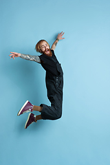 Image showing Portrait of young caucasian man looks happy, jumping on blue background