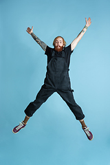 Image showing Portrait of young caucasian man looks happy, jumping on blue background