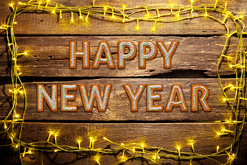 Image showing New Year wishes made of cakes on wooden table background