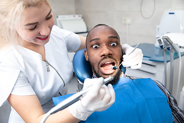 Image showing Young african-american man visiting dentist\'s office, looks scared