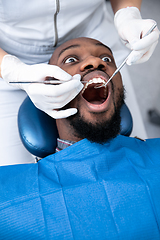 Image showing Young african-american man visiting dentist\'s office, looks scared