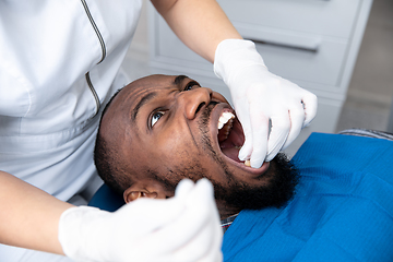 Image showing Young african-american man visiting dentist\'s office, looks scared