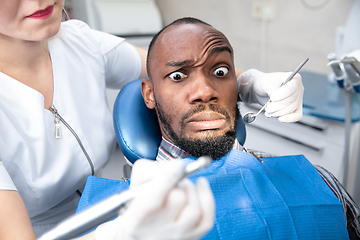 Image showing Young african-american man visiting dentist\'s office, looks scared