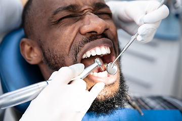 Image showing Young african-american man visiting dentist\'s office, looks scared