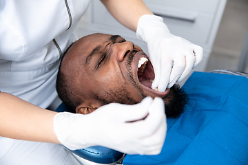 Image showing Young african-american man visiting dentist\'s office, looks scared