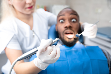 Image showing Young african-american man visiting dentist\'s office, looks scared