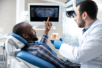 Image showing Young african-american man visiting dentist\'s office, using technologies