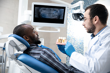 Image showing Young african-american man visiting dentist\'s office, using technologies