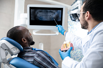 Image showing Young african-american man visiting dentist\'s office, using technologies