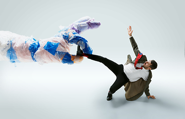 Image showing Young caucasian man avoiding big plastic hand on white studio background