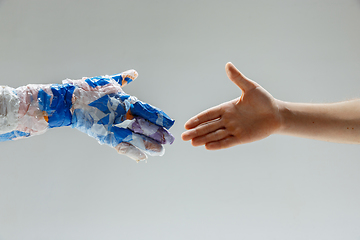 Image showing Big plastic hand made of garbage shaking another hand isolated on white studio background