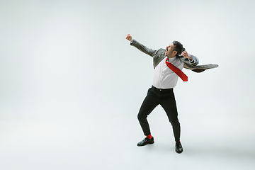 Image showing Young caucasian man moving flexible on white studio background