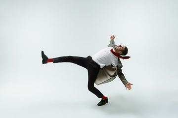 Image showing Young caucasian man moving flexible on white studio background