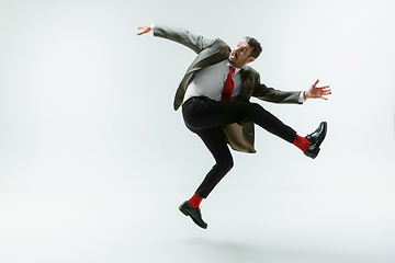 Image showing Young caucasian man moving flexible on white studio background