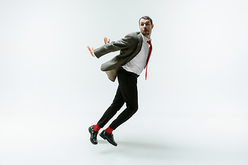 Image showing Young caucasian man moving flexible on white studio background