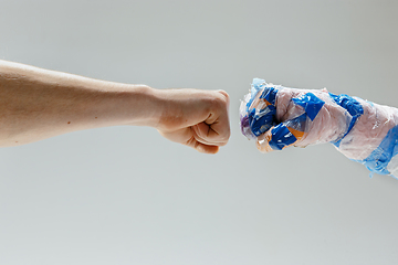 Image showing Big plastic hand made of garbage shaking another hand isolated on white studio background