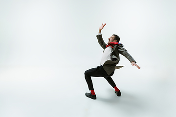 Image showing Young caucasian man moving flexible on white studio background