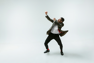 Image showing Young caucasian man moving flexible on white studio background