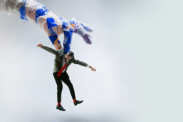 Image showing Young caucasian man avoiding big plastic hand on white studio background