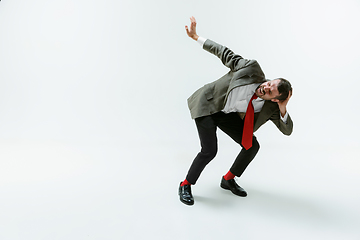 Image showing Young caucasian man moving flexible on white studio background