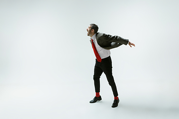 Image showing Young caucasian man moving flexible on white studio background