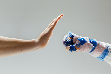 Image showing Big plastic hand made of garbage with another one isolated on white studio background