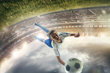 Image showing Young male soccer player kicking ball on stadium with flashlights on background