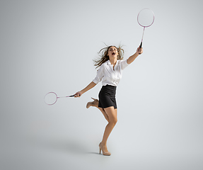 Image showing Caucasian woman in office clothes plays badminton isolated on grey studio background