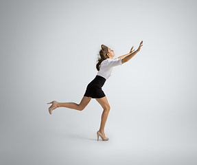 Image showing Caucasian woman in office clothes running isolated on grey studio background