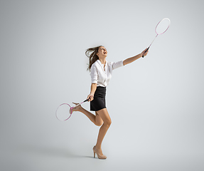 Image showing Caucasian woman in office clothes plays badminton isolated on grey studio background