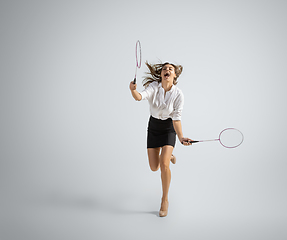 Image showing Caucasian woman in office clothes plays badminton isolated on grey studio background