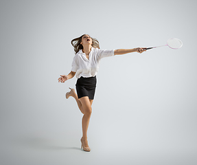 Image showing Caucasian woman in office clothes plays badminton isolated on grey studio background