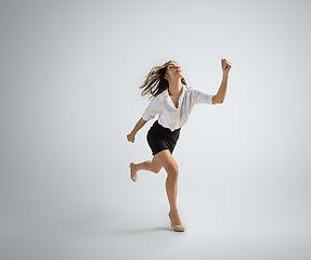 Image showing Caucasian woman in office clothes running isolated on grey studio background