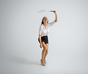 Image showing Caucasian woman in office clothes plays badminton isolated on grey studio background